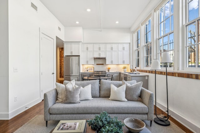 living area featuring dark wood finished floors, baseboards, recessed lighting, and a towering ceiling