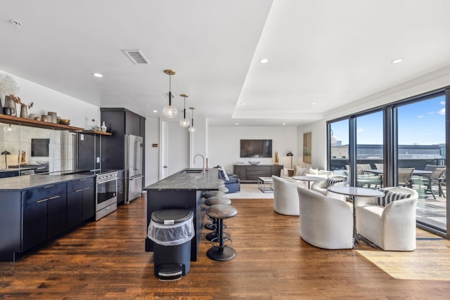 kitchen with high end refrigerator, a sink, dark wood finished floors, open shelves, and a breakfast bar area