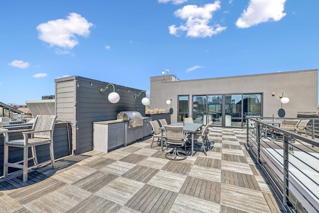 deck with outdoor dining area, a grill, and exterior kitchen