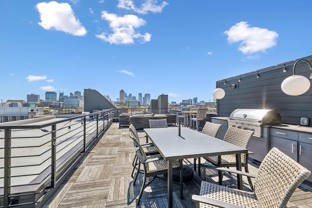deck with a skyline view, outdoor dining space, a grill, and an outdoor kitchen