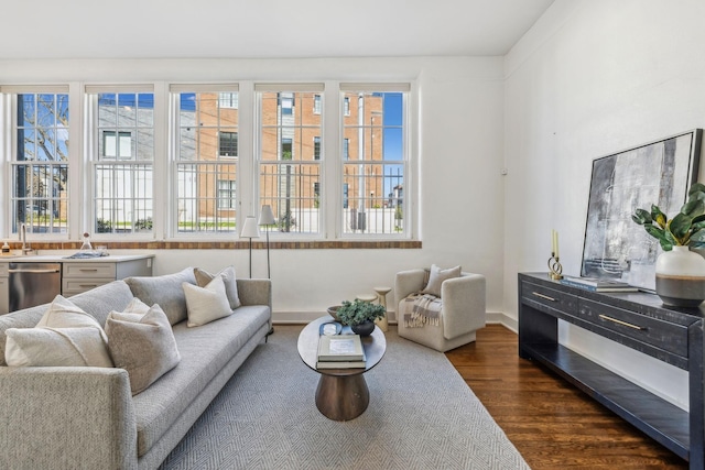 living area with dark wood-style flooring, healthy amount of natural light, and baseboards