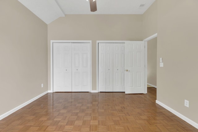 unfurnished bedroom with two closets, baseboards, high vaulted ceiling, and ceiling fan