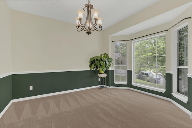 empty room featuring carpet flooring, baseboards, and a chandelier