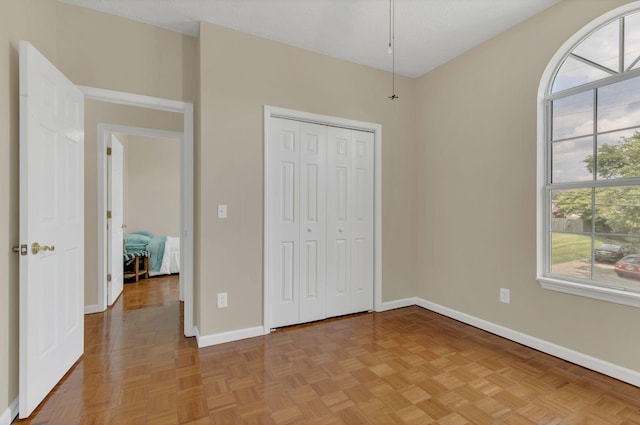 unfurnished bedroom with multiple windows, baseboards, and a closet