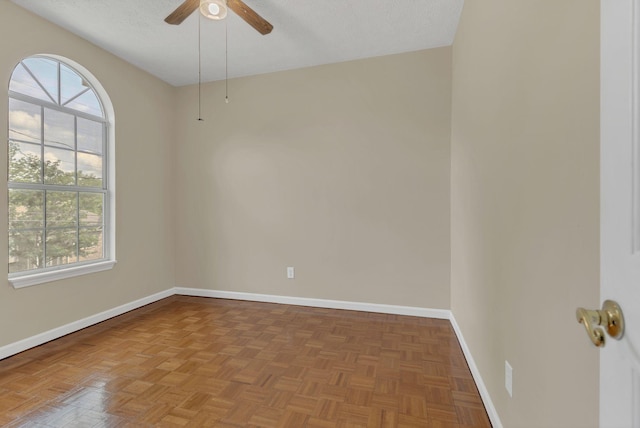 empty room with baseboards, a ceiling fan, and a textured ceiling