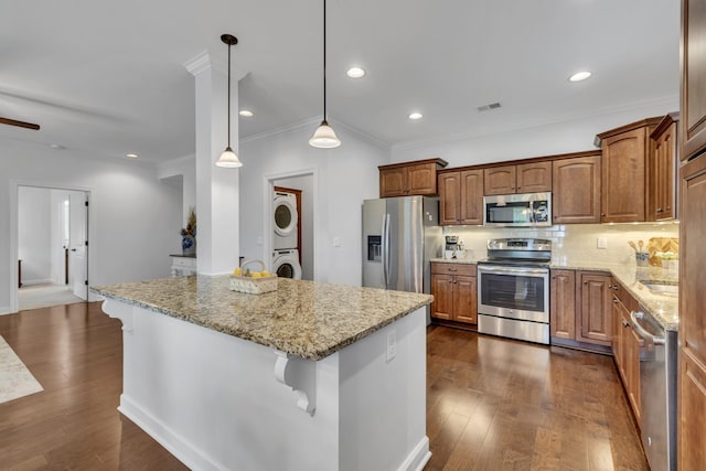 4801 Beryl Dr, Murfreesboro, TN 37128 - kitchen featuring appliances with stainless steel finishes, stacked washer and clothes dryer, a breakfast bar, ornamental molding, and dark wood-style floors