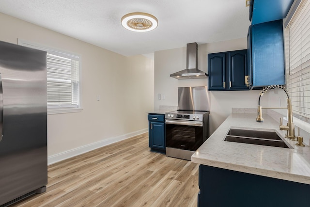 1607 Wheless St, Nashville, TN 37208 - kitchen with wall chimney exhaust hood, blue cabinets, stainless steel appliances, a sink, and light wood-style floors