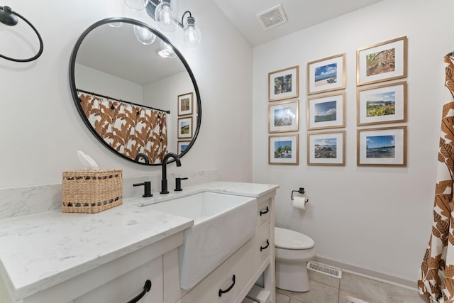 full bath featuring toilet, vanity, and tile patterned floors