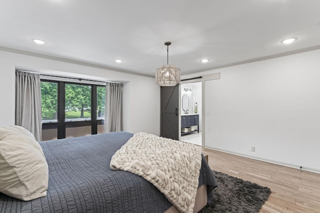 bedroom with a barn door, ornamental molding, light wood-style flooring, recessed lighting, and baseboards