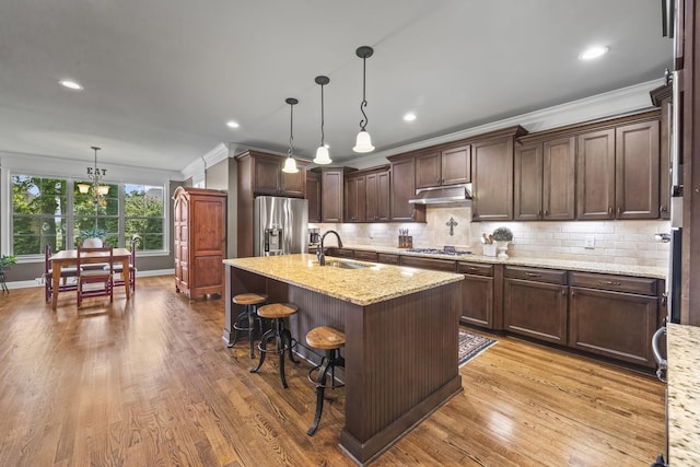 2979 Stewart Campbell Pt, Spring Hill, TN 37174 - kitchen with stainless steel appliances, a sink, ornamental molding, dark brown cabinetry, and wood finished floors