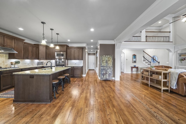 2979 Stewart Campbell Pt, Spring Hill, TN 37174 - kitchen featuring appliances with stainless steel finishes, ornamental molding, arched walkways, a sink, and a breakfast bar