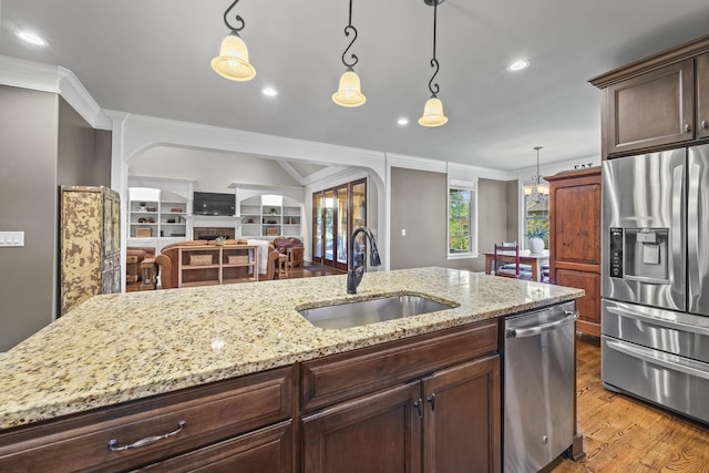 2979 Stewart Campbell Pt, Spring Hill, TN 37174 - kitchen featuring stainless steel appliances, a sink, arched walkways, light wood-type flooring, and crown molding