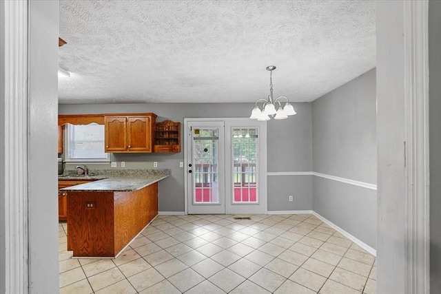 1306 Cason Trl, Murfreesboro, TN 37128 - kitchen with brown cabinets, a peninsula, light tile patterned floors, baseboards, and a chandelier