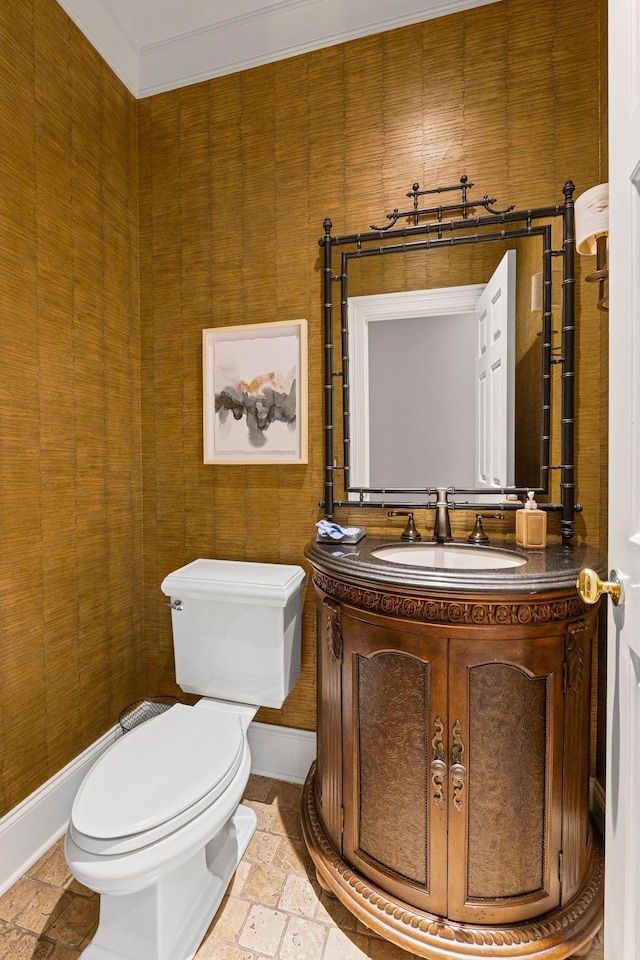 half bathroom with toilet, vanity, stone tile flooring, and baseboards