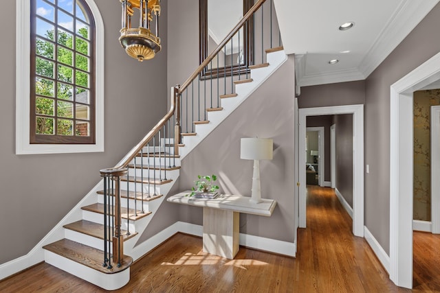stairway with baseboards, wood finished floors, crown molding, recessed lighting, and a chandelier