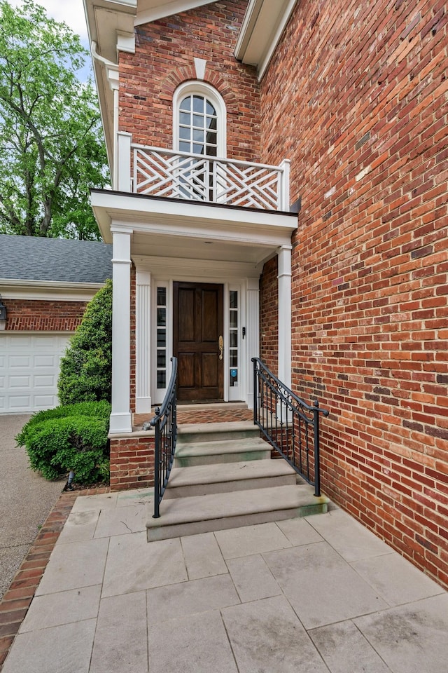 property entrance with a balcony and brick siding