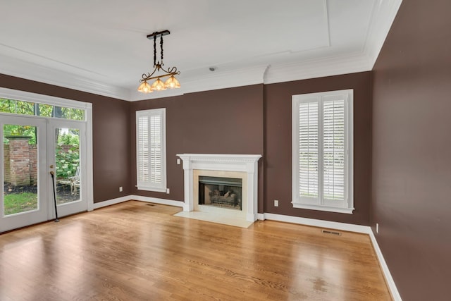unfurnished living room with a fireplace with flush hearth, wood finished floors, baseboards, and ornamental molding