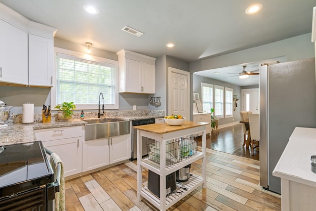 kitchen with a sink, dishwasher, black electric range, light wood finished floors, and recessed lighting