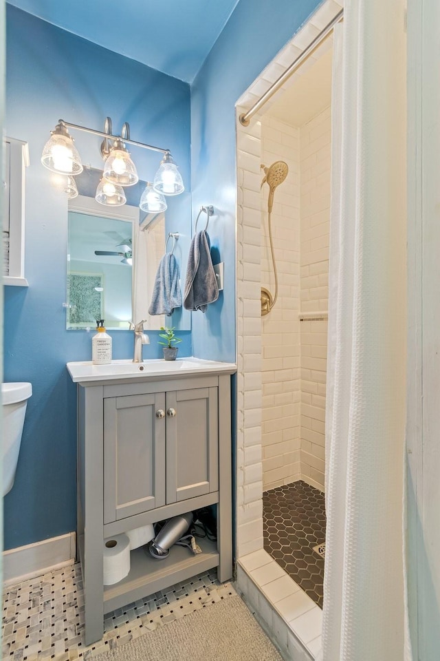 full bath featuring a stall shower, a ceiling fan, vanity, and toilet