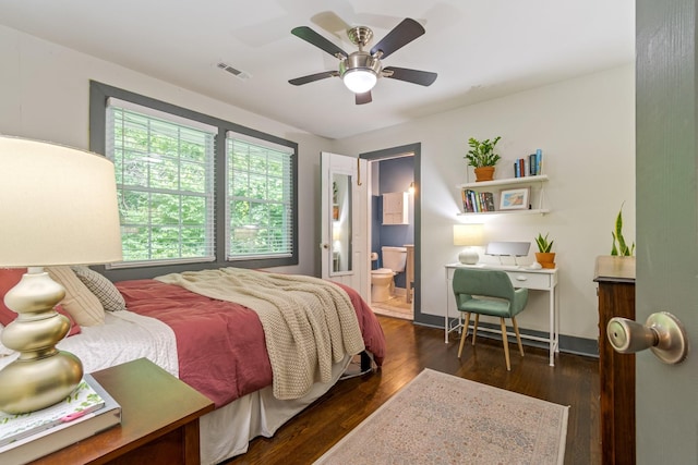 bedroom featuring wood finished floors, a desk, ensuite bath, baseboards, and a ceiling fan