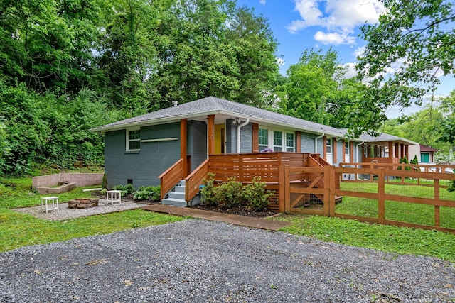 ranch-style house featuring a fire pit, brick siding, fence, and view of wooded area