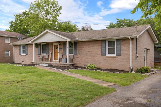 ranch-style house featuring covered porch, brick siding, a front lawn, and roof with shingles
