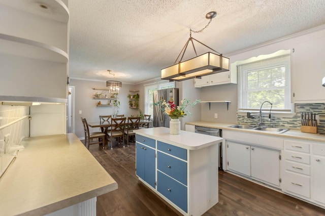kitchen featuring a sink, blue cabinetry, a textured ceiling, decorative backsplash, and a kitchen island