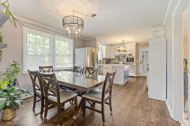 dining area with ornamental molding, a textured ceiling, a chandelier, dark wood-style flooring, and baseboards