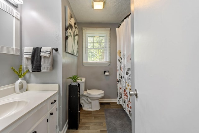 full bathroom featuring toilet, wood finished floors, a textured ceiling, vanity, and baseboards