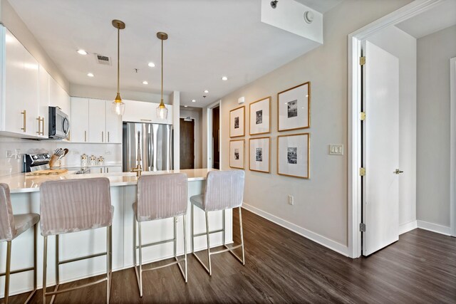 1510 Demonbreun St Unit 1012, Nashville, TN 37203 - kitchen with appliances with stainless steel finishes, a peninsula, light countertops, a kitchen breakfast bar, and dark wood-type flooring