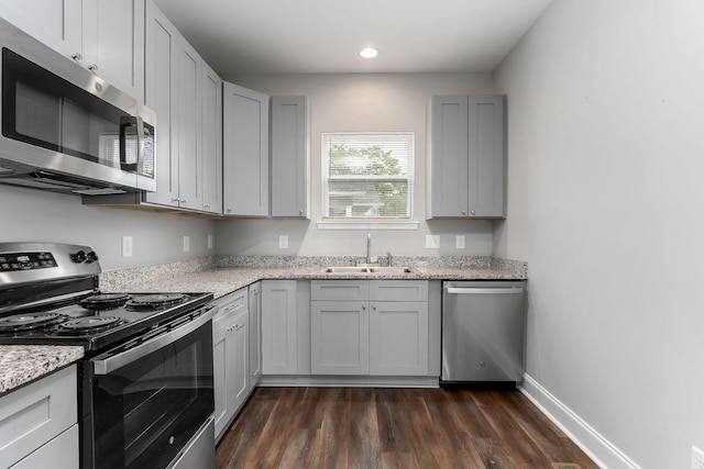 201 Hayes St, Smithville, TN 37166 - kitchen featuring appliances with stainless steel finishes, a sink, dark wood-style flooring, gray cabinets, and light stone counters
