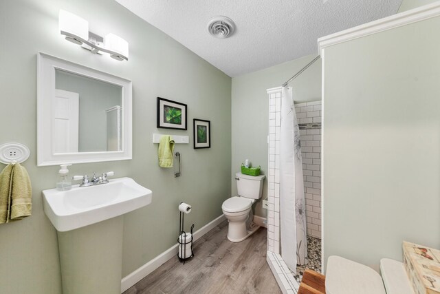1205 Parker Dr, Pulaski, TN 38478 - full bath with toilet, a tile shower, wood finished floors, a textured ceiling, and baseboards