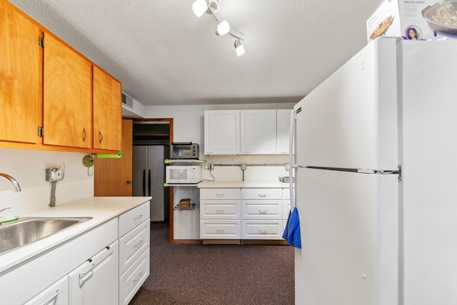 1205 Parker Dr, Pulaski, TN 38478 - kitchen with white appliances, a textured ceiling, dark colored carpet, light countertops, and a sink