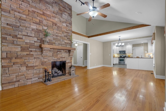 220 Porters Bluff Rd, Clarksville, TN 37040 - unfurnished living room featuring a ceiling fan, a chandelier, high vaulted ceiling, a stone fireplace, and light wood-type flooring