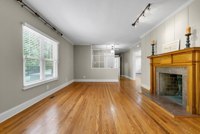 220 Porters Bluff Rd, Clarksville, TN 37040 - unfurnished living room featuring track lighting, light wood-style floors, a tile fireplace, baseboards, and ornamental molding