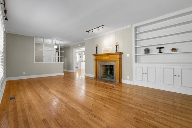 220 Porters Bluff Rd, Clarksville, TN 37040 - unfurnished living room featuring rail lighting, a high end fireplace, light wood-style floors, baseboards, and built in features