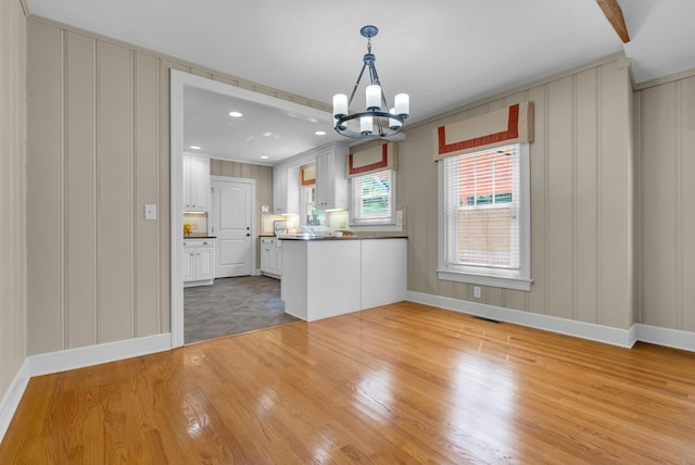 220 Porters Bluff Rd, Clarksville, TN 37040 - kitchen featuring a decorative wall, a peninsula, a chandelier, baseboards, and light wood finished floors