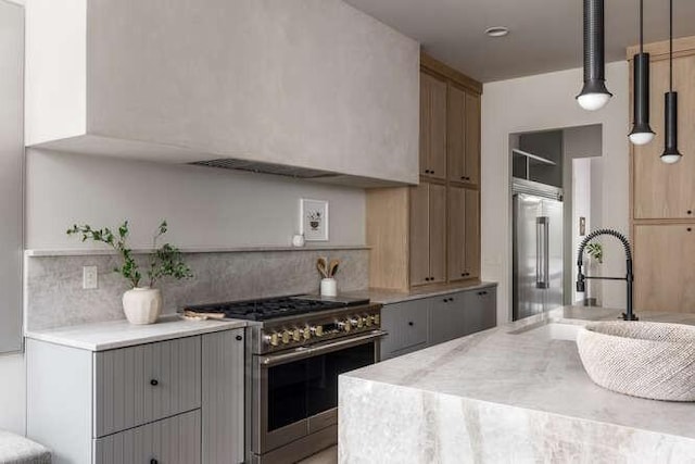 kitchen with high end appliances, light countertops, a sink, and backsplash