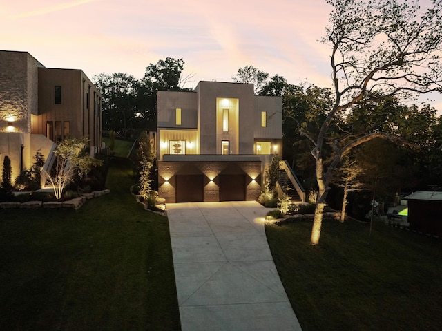 contemporary home featuring concrete driveway, stairs, a front lawn, and a garage