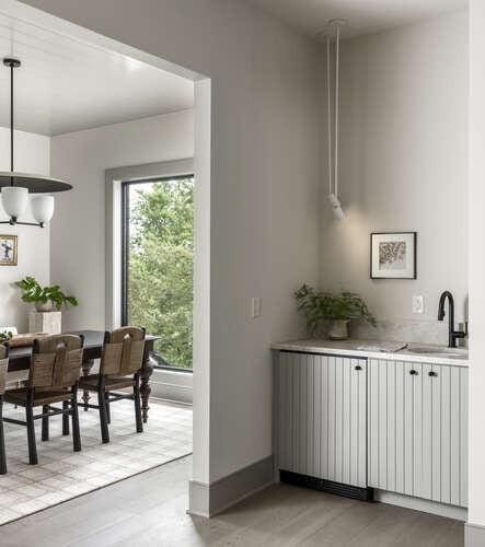 bar area with light wood-type flooring, a sink, baseboards, and hanging light fixtures