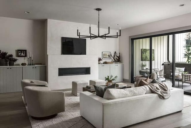 living area with wood finished floors, a large fireplace, and a chandelier