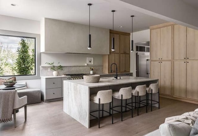 kitchen with light brown cabinets, appliances with stainless steel finishes, a breakfast bar area, light countertops, and light wood-type flooring