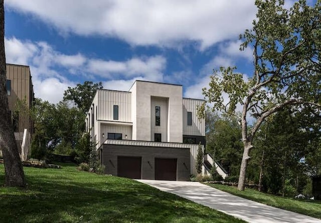 modern home featuring an attached garage, a front lawn, concrete driveway, and board and batten siding