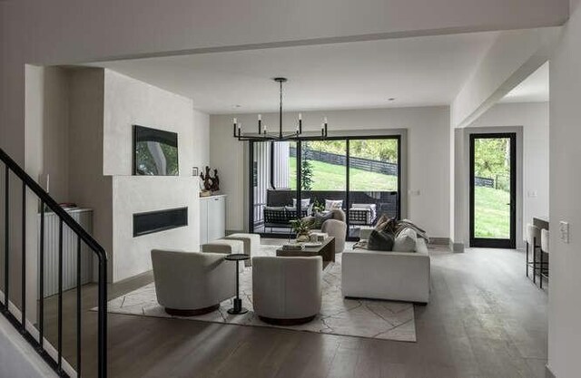 living area featuring a fireplace, wood finished floors, stairway, and a chandelier