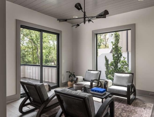 living area with baseboards, a chandelier, and wooden ceiling