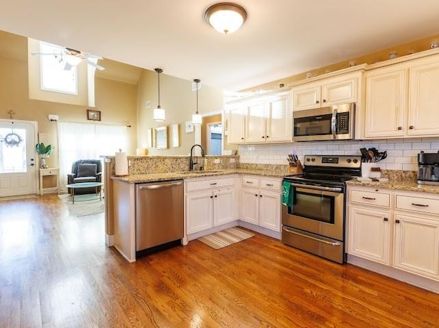 302 Janie St, Smyrna, TN 37167 - kitchen with appliances with stainless steel finishes, a sink, a peninsula, tasteful backsplash, and light wood finished floors
