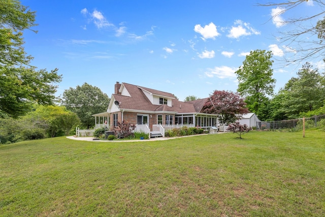back of property featuring a sunroom, a chimney, a storage shed, and an outbuilding