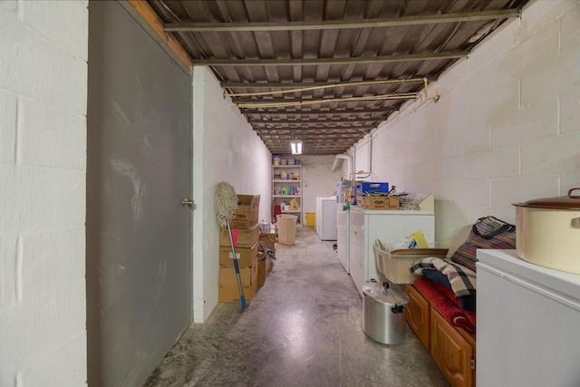 unfinished below grade area featuring washing machine and clothes dryer and concrete block wall