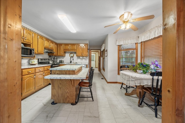 kitchen featuring appliances with stainless steel finishes, under cabinet range hood, light countertops, a sink, and ceiling fan