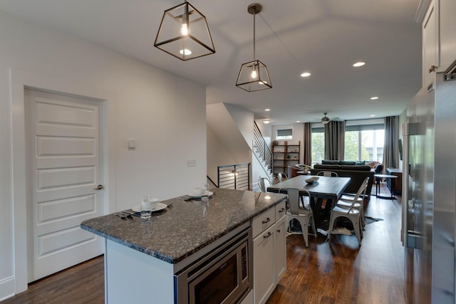 kitchen with stainless steel microwave, dark wood-style flooring, a center island, white cabinets, and recessed lighting